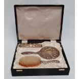 A silver repousse mirror and brush set - Birmingham 1984, decorated with scrolls, foliage and masks,