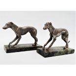 A pair of early 20th century spelter greyhounds - each raised on a rectangular green marble base,
