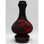 A Chinese cinnibar and black lacquer vase - of bottle form, decorated with foliage on a diapered
