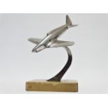 A chrome desk paperweight - modelled as a swooping fighter aircraft on a taupe marble base, height