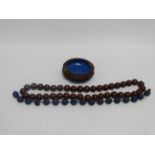 A string of pierced blue enamel beads - length 23cm, together with a string of polished hardwood