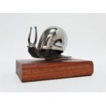 A chrome car mascot - modelled as a snail, now mounted on a teak plinth, 11cm wide