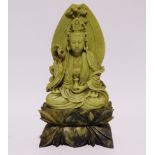 A soapstone carving of a Buddhist figure - seated on a stylised foliate plinth, height 31cm.