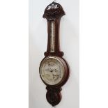 An early 20th century oak aneroid barometer - carved with foliage, with a silvered dial and