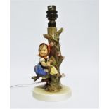 Hummel - a table lamp modelled with a young girl seated amongst branches, height 24cm.