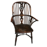 A Windsor style armchair - with a pierced wheel splat above a solid contoured seat and with turned