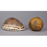 A 19th century carved cowrie shell - carved with the Lords Prayer, width 9cm, together with a seed