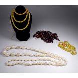 A graduated string of hardstone beads - of oval form, together with a string of ruby glass beads and