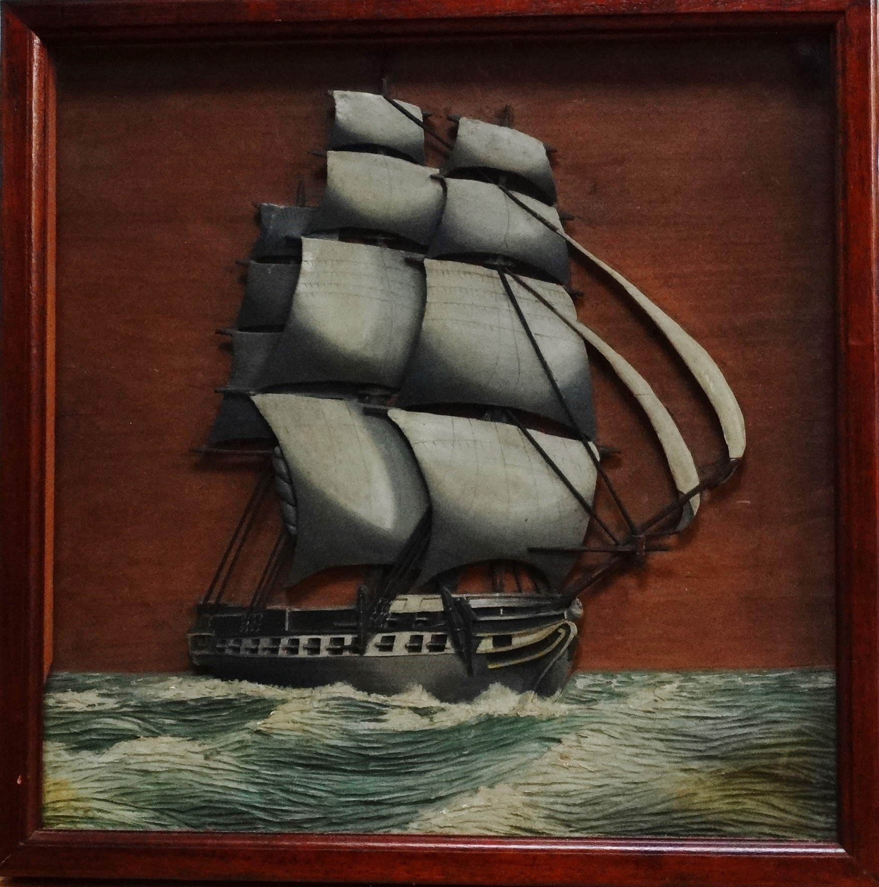 An early 20th century wooden diorama - depicting a frigate at sea, framed and glazed, 48 x 48cm.