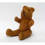 An early 20th century teddy bear - golden plush with articulated limbs, height 16cm.