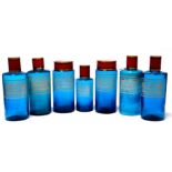 A set of seven pale blue apothecary jars - cylindrical with etched contents labels and red and