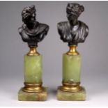 A pair of spelter busts of Apollo and Diana - raised on onyx and gilt metal columnar supports,