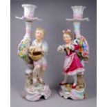 A pair of early 20th century Meissen style candlesticks - modelled with figures of a young boy and