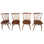 A set of four Ercol dining chairs - with stick backs and solid contoured seats on turned tapering