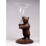 A late 19th century Black Forest bear - carved holding an engraved glass stem vase flute, height
