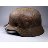 A German WWII Stahl helmet - retains remnants of unit decals, extensive battle damage and subsequent