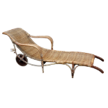 In the manner of Harry Peach - a cane sun lounger with open arms and integral handles and with
