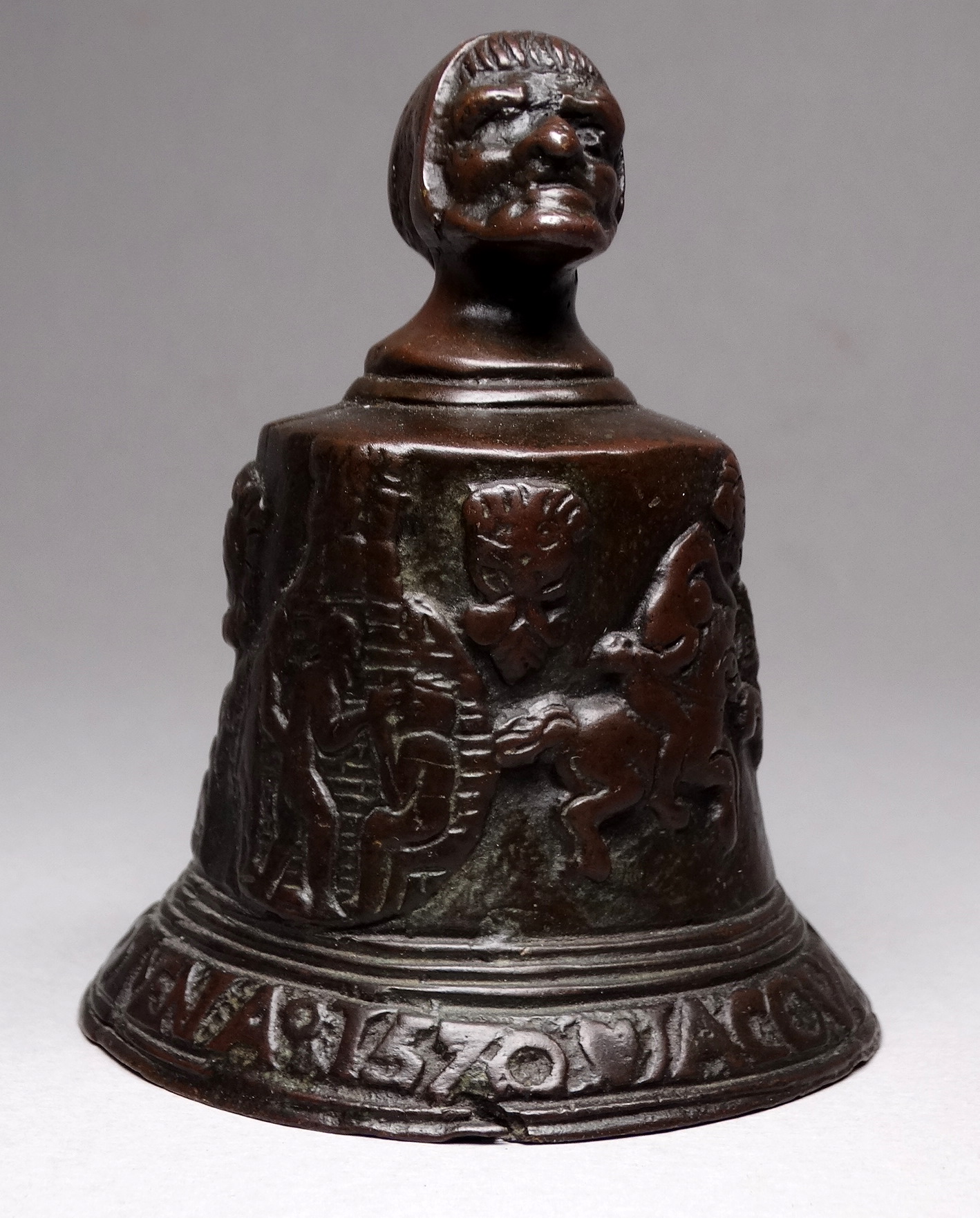 After the antique, a 19th century cast bronze bell - with grotesque mask, height 10cm.