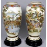 A pair of early 20th century Satsuma vases - decorated with figures crossing a bridge, on turned