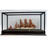 A wooden model of a four masted schooner - in a glass case, width 55cm, height 27cm.