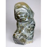 An Inuit soapstone carving - modelled as a woman skinning a seal, height 20cm.