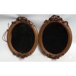 A pair of late 19th century oval gilt framed wall mirrors - with ribbon ties at top and bottom,