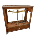 A set of early 20th century brass laboratory scales - in glazed hardwood case with weights, width