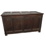 A 17th century oak coffer - the four panel hinged cover above a panelled front and raised on stile