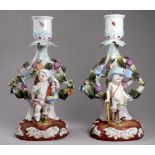 A pair of Sitzendorf candlesticks - modelled with cherubs standing on naturalistic bases, height