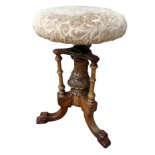 A Victorian walnut piano stool - the circular upholstered seat above a circular column on tripod