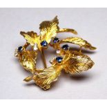An 18ct yellow gold brooch set with diamonds and sapphires - circular form set with leaves, 14.2 g