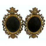 A pair of early 20th century cast gilt metal mirrors - with bevelled oval plates within foliate