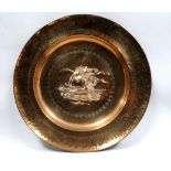 A large repousse brass charger - decorated with a galleon sailing towards a sunset, diameter 56cm.