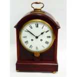 A late 19th century mahogany table clock - the domed case surmounted by a brass handle, with a white