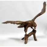 A 20th century cast brass eagle - wings open and standing on a branch, height 50cm.