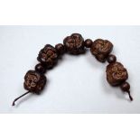 A strand of five Chinese carved hardwood Buddha head beads - each comprising four faces, bead size