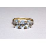 A three stone 9ct yellow gold dress ring - the aqua coloured stones claw set with diamond studded