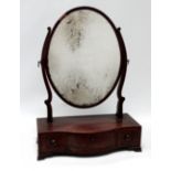 A 19th century mahogany toilet mirror - the oval plate between shaped supports and serpentine plinth