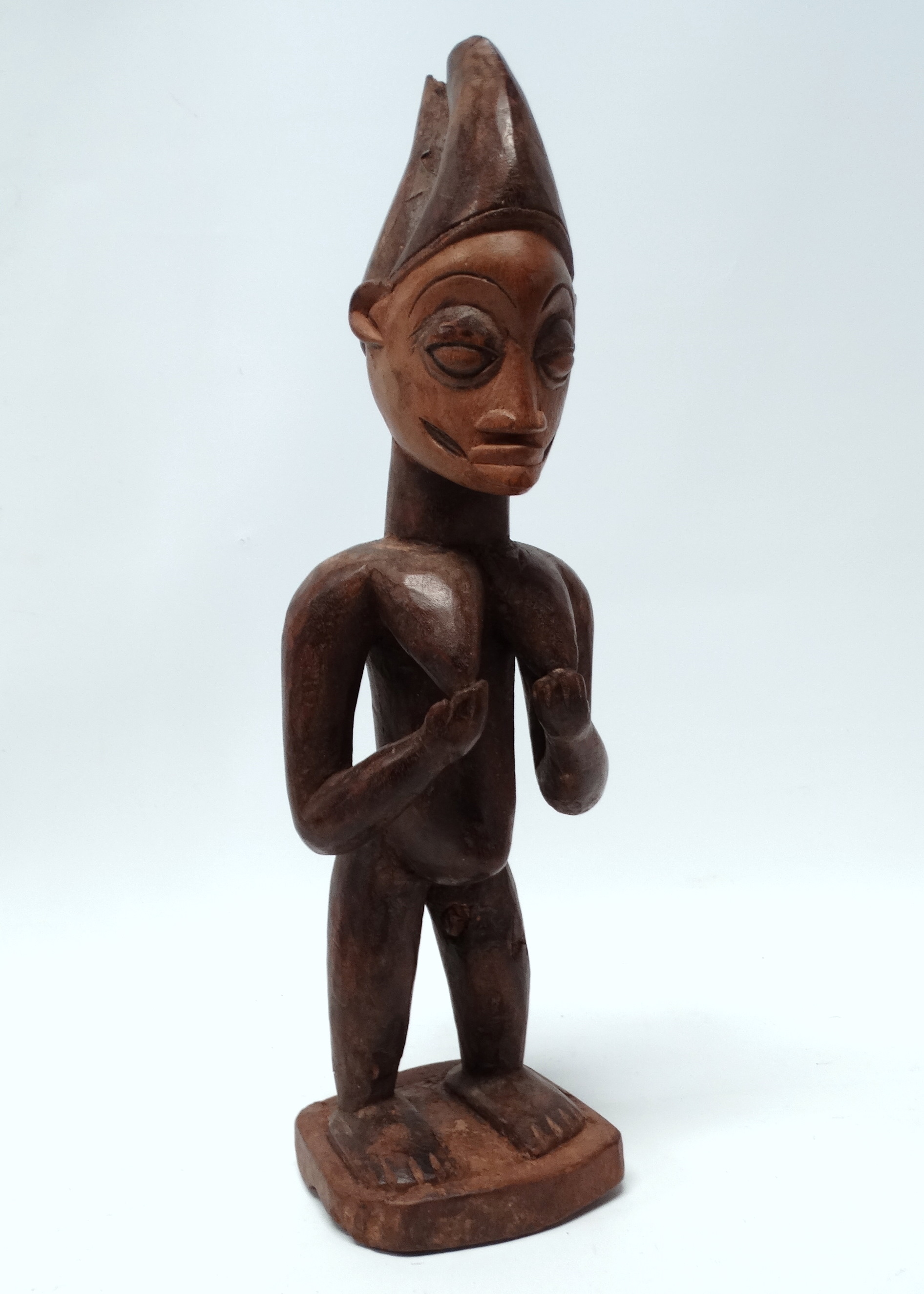 A Yoruba fertility figure - the standing female with bleached face and wearing a bifurcated hat,