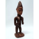 A Yoruba fertility figure - the standing female with bleached face and wearing a bifurcated hat,