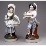 A pair of 19th century German figures - male and female flower sellers, carrying baskets and hods,