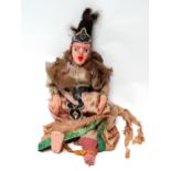 A 20th century Indonesian doll - with painted wooden head and hands the fabric body in traditional