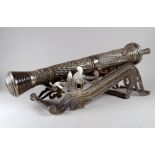 A white metal table cannon - possibly Turkish, decorated with foliate repousse panels on a