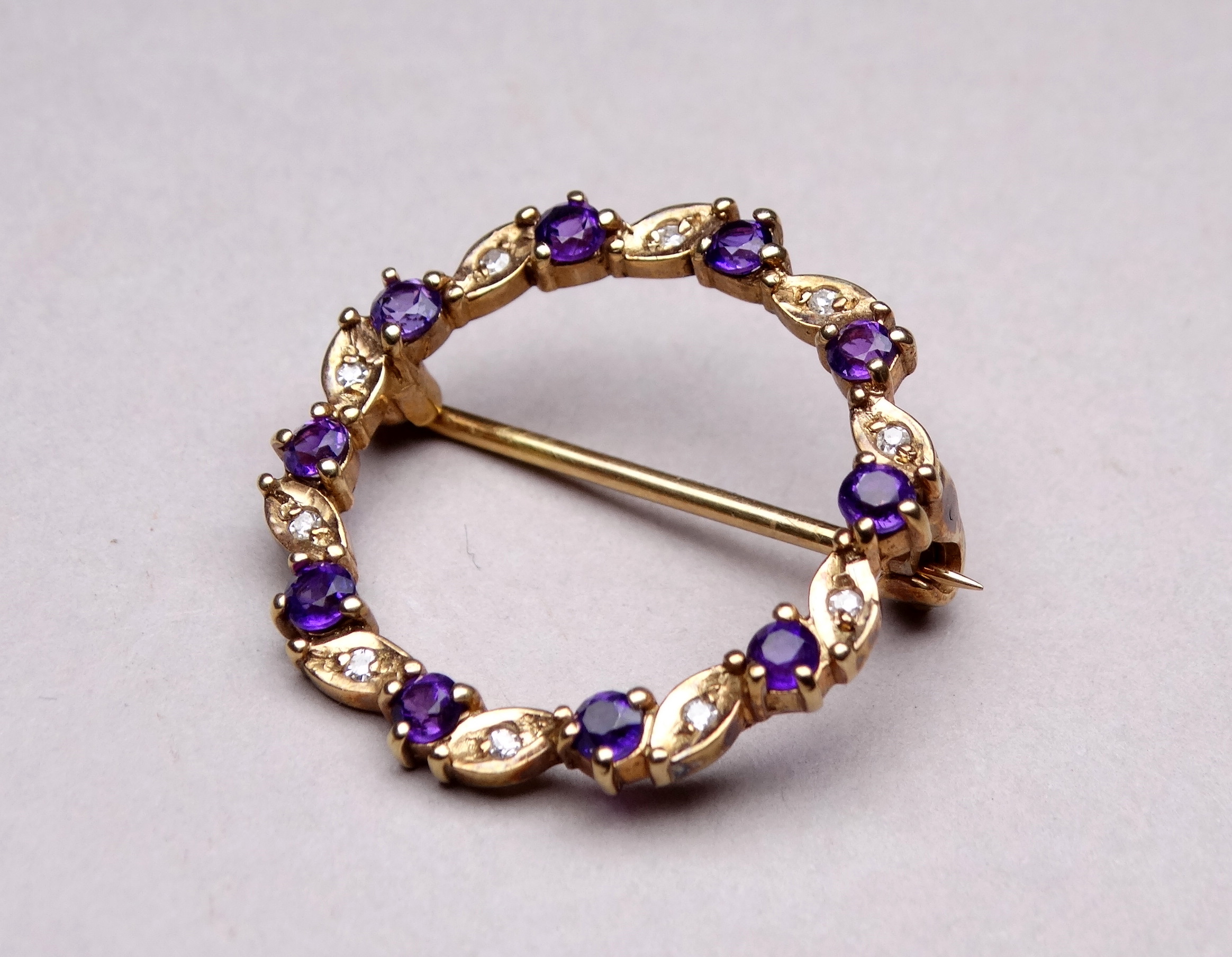 A 9ct yellow gold amethyst and diamond annular brooch - with a leaf setting, weight 2.8g.