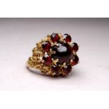 A 9ct yellow gold and garnet ring - the cluster setting with a cabochon central stone, ring size