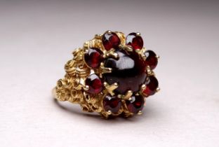 A 9ct yellow gold and garnet ring - the cluster setting with a cabochon central stone, ring size