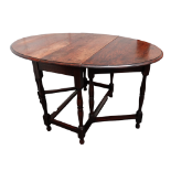 A 17th century style oak drop leaf table - the oval top above square and turned legs joined by