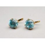 A pair of blue topaz earrings - the circular faceted stone set in yellow metal, possibly 9ct, weight