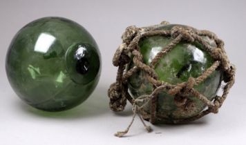 Two early 20th century green glass fishing floats - one in original net, each diameter 13cm.