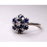 An 18ct white gold blue topaz and diamond set ring - the cluster setting in three steps, ring size